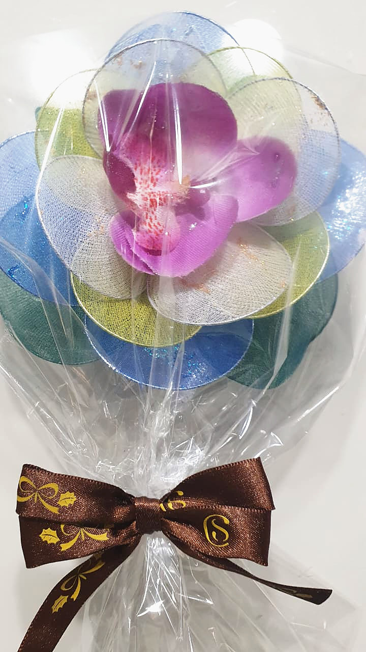 Flor de meia de seda em tons de azul e lilás, embalada em celofane com laço marrom