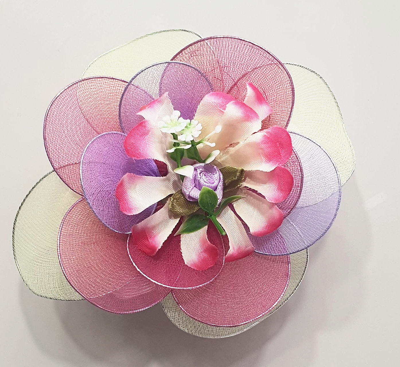 Flor de meia de seda em tons de rosa, lilás e verde-claro, com miolo de pétalas pintadas